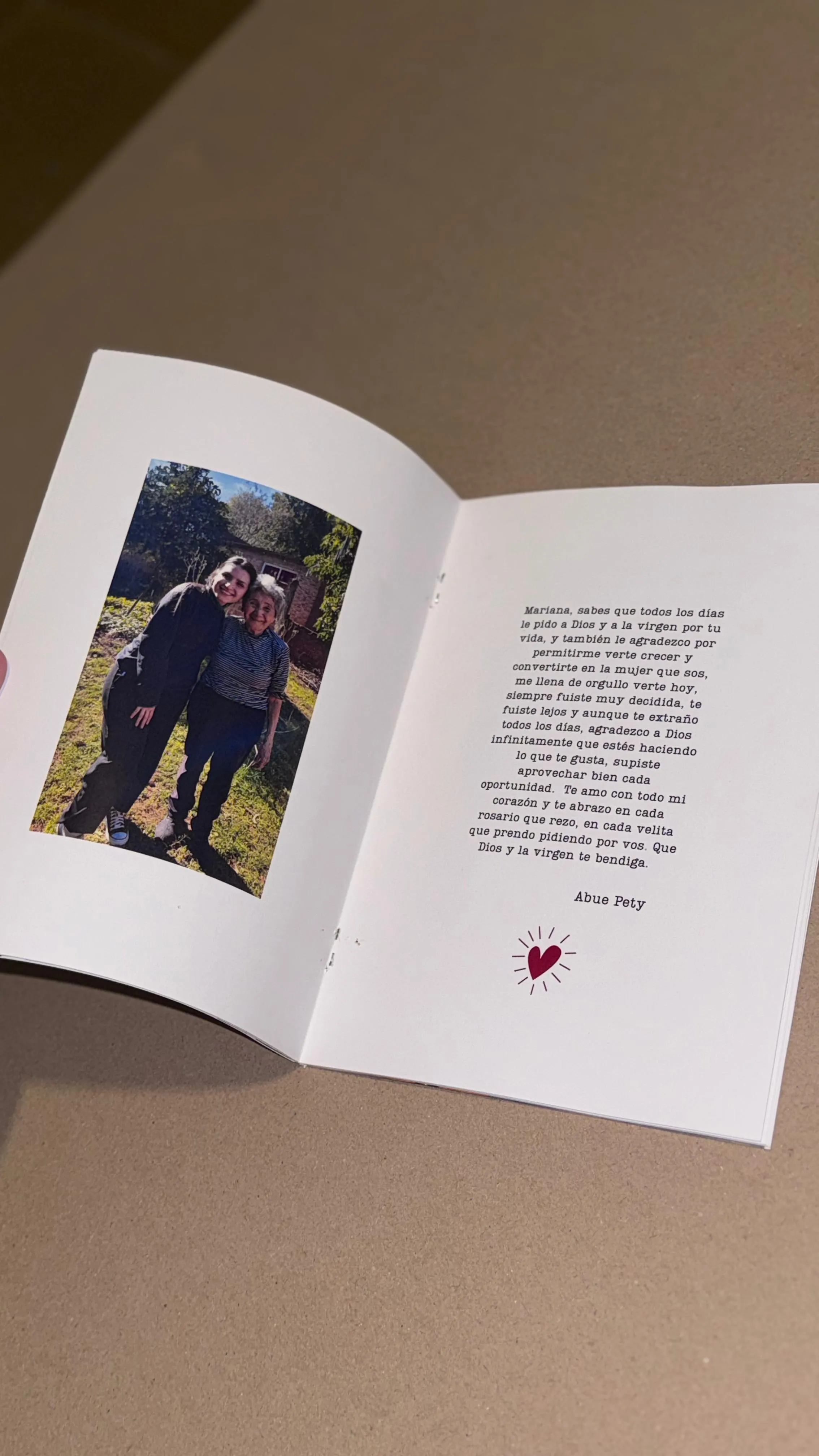 Página de un fotolibro con una foto de una abuela y su nieta, y una carta escrita a máquina dedicada a Mariana